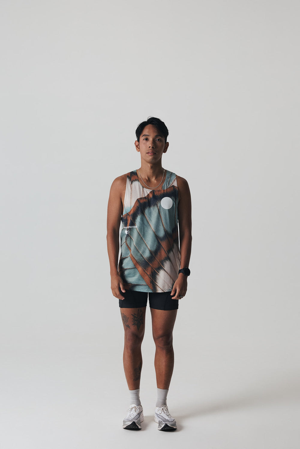 Participation butterfly singlet, breathable mesh, teal–tan wing print, white circle logo on chest.