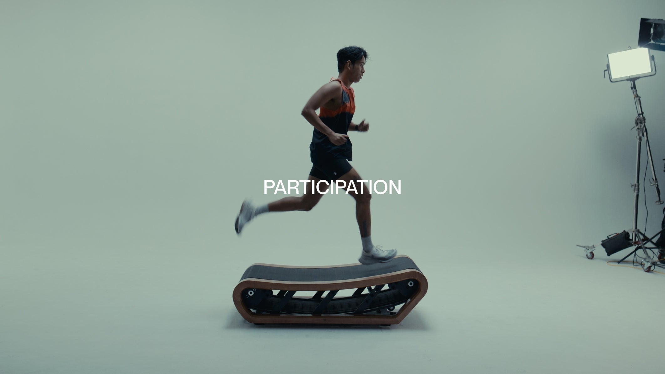 Man running with a Participation singlet tank top on a treadmill